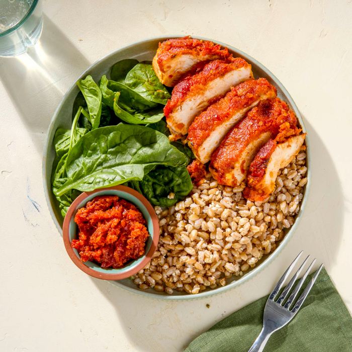 Roasted chicken breast with romesco sauce over farro and spinach